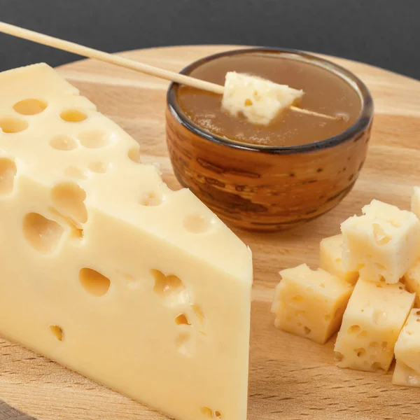 黄色のマダムチーズ 穴の木製の背景を持つ三角形のピースチーズ — ストック写真
