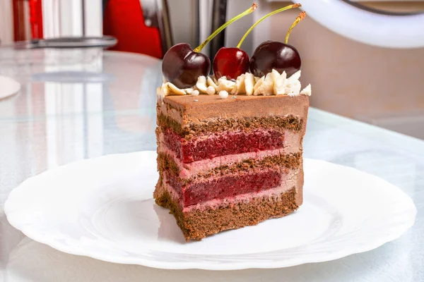 Detail on a Slice of a Black forest cake, or traditional austria schwarzwald cake from dark chocolate and sour cherries on white table