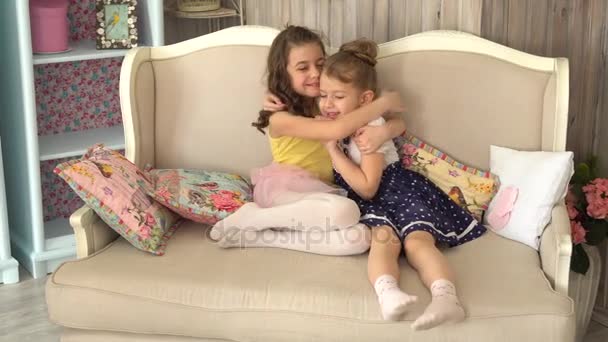 Маленька сестра обіймається сидячи на дивані — стокове відео