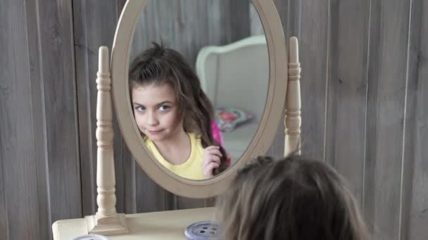 Niña haciendo maquillaje y peinado sentada frente a un espejo — Vídeo de stock