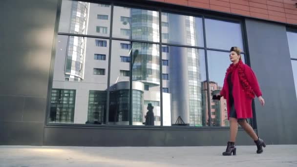 Αυτοπεποίθηση γυναίκα με ένα όμορφο ασυνήθιστο κομμωτι βόλτες μέσα στην πόλη της άνοιξης. Κορίτσι στο φόντο της σύγχρονης αρχιτεκτονικής. Αργή κίνηση — Αρχείο Βίντεο
