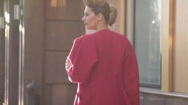 Kendine güvenen güzel bir olağandışı hairdress kadınla bahar kentin içinde yürür. Arka plan, modern mimarinin kız. Ağır çekim