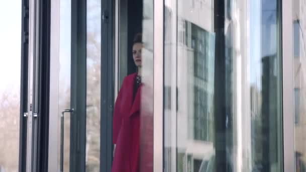 Une femme confiante sort de la porte. Fille sur le fond de l'architecture moderne. MOTION DE LENT — Video