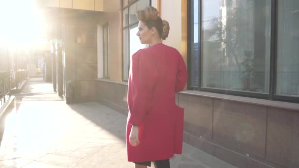Självsäkra kvinnan med en vacker ovanlig frisörsal promenader genom våren staden. Flicka på bakgrund av modern arkitektur. Slow Motion — Stockvideo