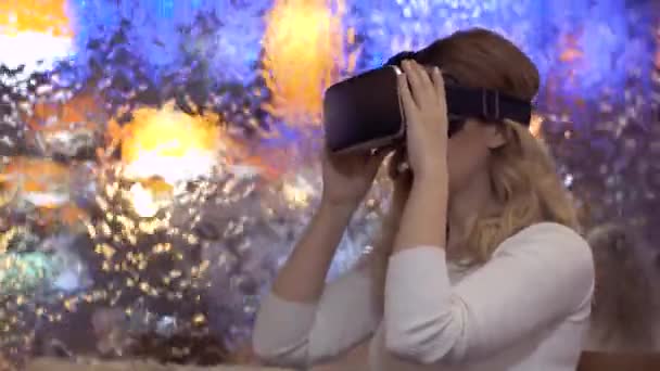 Vrouw zet op en maakt gebruik van virtual reality bril op een abstracte achtergrond — Stockvideo