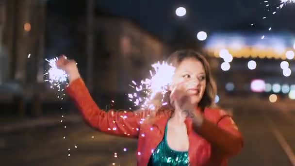 Chicas hermosas jóvenes con bengalas bailando felizmente con las manos en alto con la música en la ciudad de la noche. Movimiento lento — Vídeos de Stock