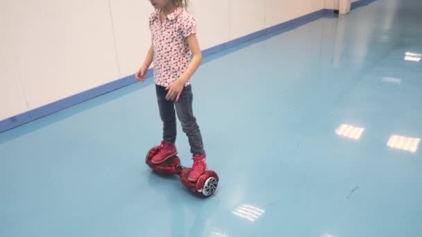 Liten flicka rider en hyroscooter. barn lär sig att rida på segway — Stockvideo