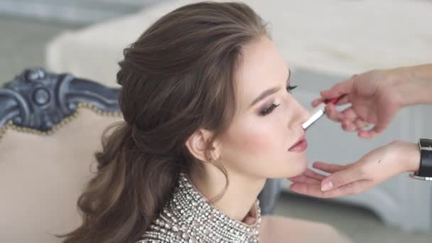 Maquillaje de una encantadora joven morena. Hermosa chica en un vestido de noche maquillaje y peinado — Vídeos de Stock