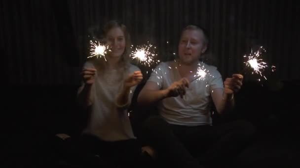 Jovem e cara segurando sparklers e sorrindo. câmara lenta — Vídeo de Stock