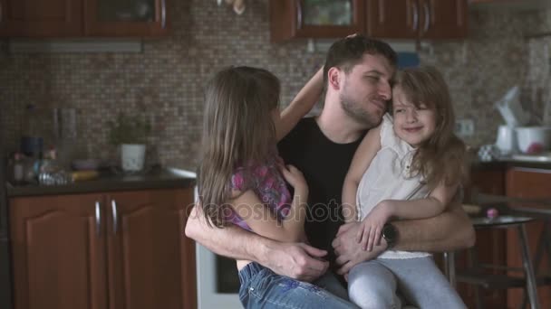 Papá besa y abraza a sus hijas sentadas en su regazo. padre e hijos. cámara lenta — Vídeos de Stock