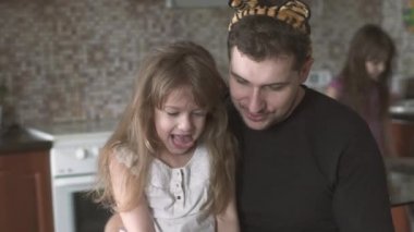küçük kızı gözünü babalar dizlerine oturur ve ona çizdiği gösterir. Baba ve küçük kızı gülmek, gülümsemek ve birlikte vakit geçirmek.