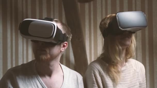 Девушка и ее парень держатся за руки и погружаются в мир виртуальной реальности очки виртуальной реальности — стоковое видео