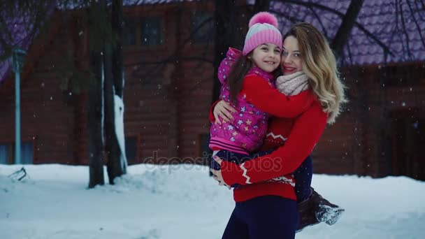 Retrato de madre e hija. Una niña en brazos de sus madres en el bosque de invierno. Mamá e hija dan un paseo en invierno. cámara lenta — Vídeos de Stock