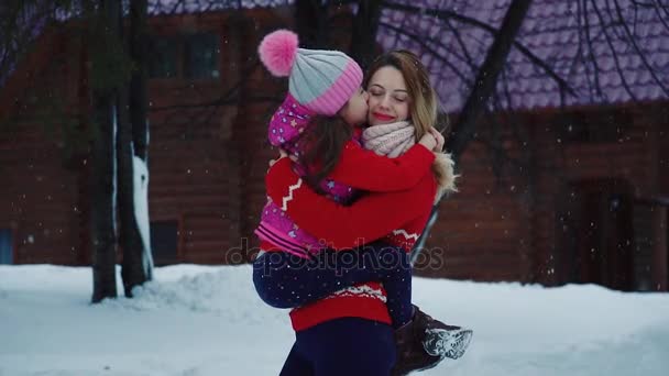 Small daughter hugs and kisses her mother. Mom and child on a walk in the winter forest. parent walks with a child in a borrowed park. slow motion — Stock Video