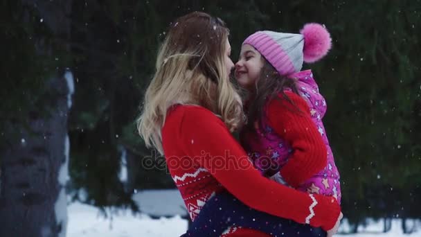 Προσωπογραφία της μητέρας και της κόρης. Ένα κοριτσάκι στην αγκαλιά της μητέρες μέσα στο δάσος του χειμώνα. Μαμά και κόρη για μια βόλτα το χειμώνα. αργή κίνηση — Αρχείο Βίντεο
