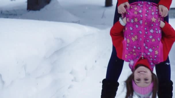 Mãe brinca e se diverte com sua filha para um passeio na floresta de inverno. câmara lenta — Vídeo de Stock