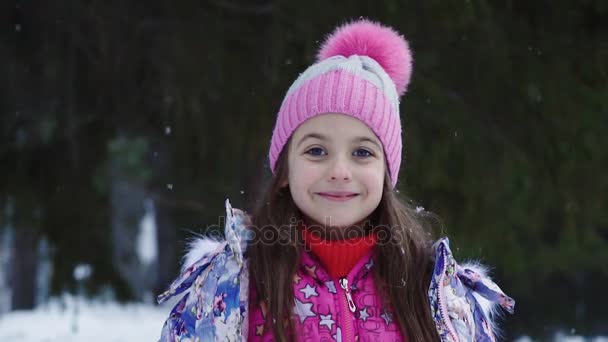 Close-up retrato de uma menina sob a neve. criança em passeio de inverno. câmara lenta — Vídeo de Stock