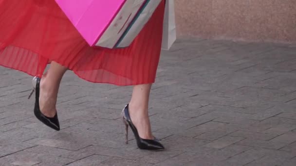 Füße Nahaufnahme eines Mädchens, das mit Einkaufstüten die Straße hinunterläuft. Zeitlupe — Stockvideo