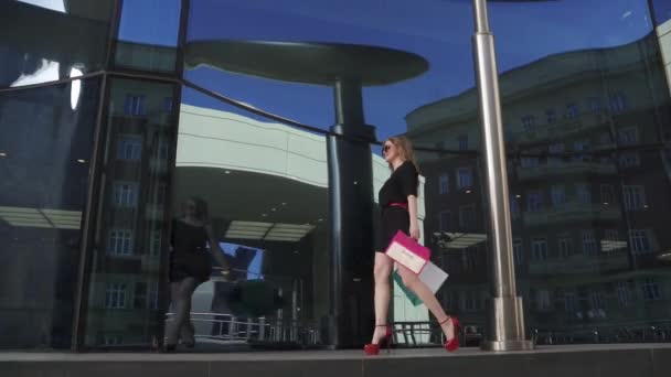 Jolie fille vient avec des sacs pour faire du shopping dans les mains près de la vitrine. MOTION DE LENT — Video