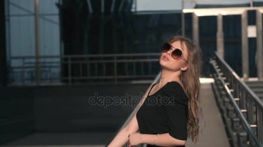 Siyah elbise ve güneş gözlüğü yaz şehir zemin karşı güzel bir genç kız portresi. ağır çekim