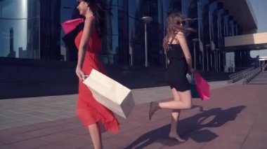Güzel genç kızlar ile başarılı alışveriş mutluyuz. Kız arkadaşlarınla dans gülümseme ve eğleniyor elinde alışveriş için paketleri. Arkadaşlar şehirde birlikte vakit. Ağır çekim