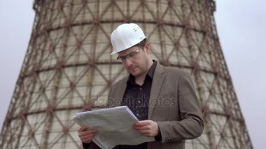 genç mimar güç istasyonu arka plan üzerinde. bir çizim tutan çekici erkek Tasarımcısı. Soğutma Kulesi nükleer santral. yanan kömür Santrali