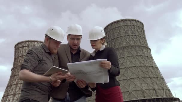 Gruppe von Architekten und Planern zum Hintergrund des Kernkraftwerks. die Probleme der Luftverschmutzung, des Umweltschutzes, der Kohlenstoffemissionen und der globalen Erwärmung. Konstrukteure in Bauhelmen. — Stockvideo