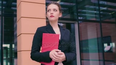 Çekici genç iş kadını bir toplantı için bekliyor. İş elbiseleri kız ile kırmızı bir klasörde bir iş merkezi arka plan üzerinde eller. Ağır çekim