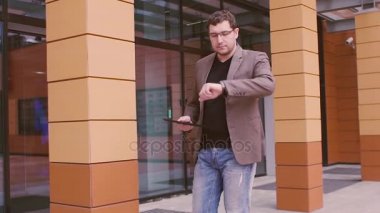 Üstünde belgili tanımlık gitmek bir tablet bilgisayarda çalışan Modern işadamı hippi. Genç çekici adam akıllı bir saate benziyor. Elinde akıllı izlemek ve tablet bilgisayar.