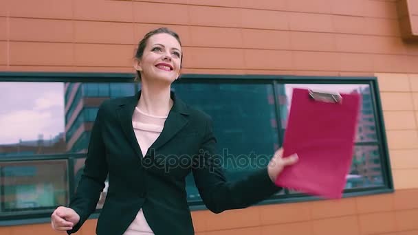 La chica sonriente es bailes felices e incendiarios. hermosa mujer en el fondo del edificio de negocios. MOCIÓN LENTA — Vídeos de Stock