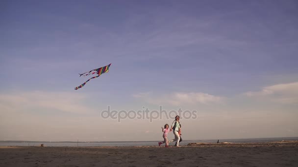 Mamma trascorre del tempo con i bambini all'aperto al tramonto sul mare. la famiglia gestisce un aquilone e felice primavera.. slow motion — Video Stock