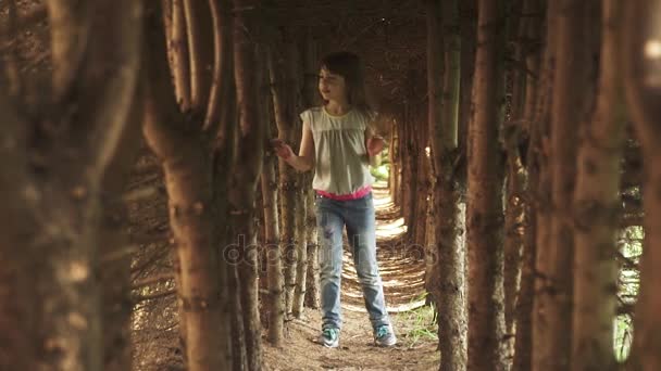 Little girl walks through the tunnel of trees. the child in the mysterious and magical forest. slow motion — Stock Video