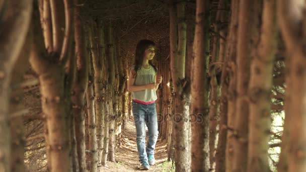 Маленька дівчинка проходить через тунель дерев. дитина в таємничому і чарівному лісі — стокове відео