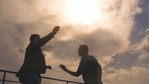 Silueta de dos hombres de negocios celebrando un éxito. El hombre le da cinco a un colega. cámara lenta — Vídeos de Stock