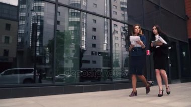 bir modern iş merkezi arka planda yürüyen emin iş kadın. Kız planları holding ve üstünde belgili tanımlık gitmek konuşuyor. kadın sokakta iş giysileri. Ağır çekim
