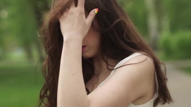 Retrato de chica atractiva joven con una hermosa sonrisa. el modelo mira a la cámara y sonríe. chica en un brillante vestido de verano en el Parque. cámara lenta — Vídeos de Stock