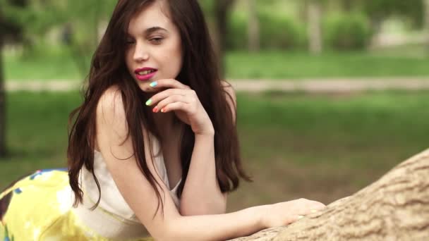 Mooi meisje droomt in het Park liggend op een boomtak. mooie brunette glimlachend en lachen. Slow motion — Stockvideo