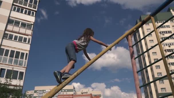 Enfant joue sur l'aire de jeux parmi les maisons. la jeune fille monte au sommet des escaliers . — Video