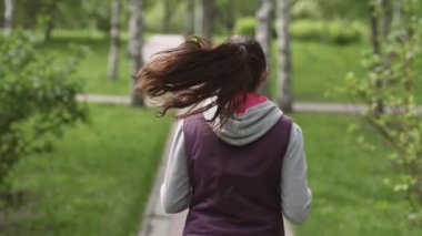 çalışan kız. Genç bir atlet yaz park, arkasından bir görünümü aracılığıyla çalışır. Kamera modeli izler. Ağır çekim