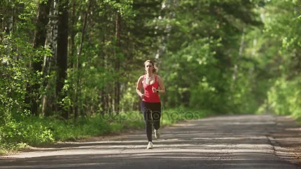 Mladá žena běhání v lese v létě. dívka jde sporty v přírodě. model běží směrem k fotoaparátu. — Stock video