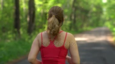 genç kadın yaz ormanda koşu. Kız spor doğada gider. sporcular bokeh geri. ağır çekim