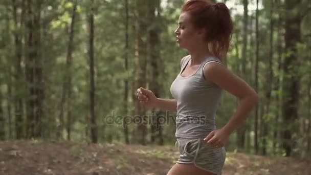 Крупный план портрета привлекательной рыжеволосой девушки на пробежке по лесу. замедленное движение — стоковое видео