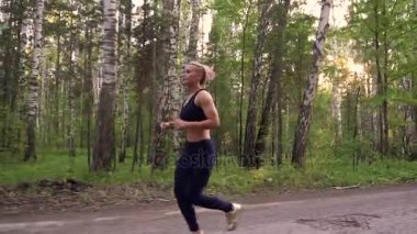 güçlü kız bir yaz ormanda koşu. kas atlet doğada çalışıyor. ağır çekim