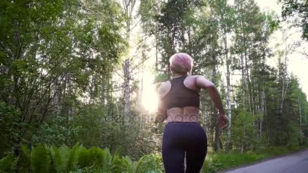 Молодая девушка на пробежке тренируется в лесу. Спортсмен в спортивной одежде на тренировке. замедленное движение — стоковое видео
