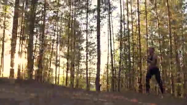 Girl runs lightly uphill. Beautiful sportswoman in training in the woods at sunset — Stock Video