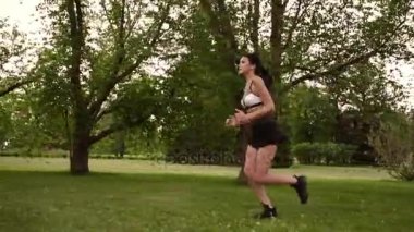 Kız parkta koşu. Genç kadının doğa spor yapması. ağır çekim