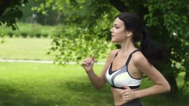 Yakın çekim portre bir atlet. Ormanda çalışan kız. Genç kadının doğa spor yapması. ağır çekim
