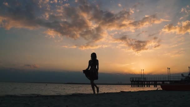 Flickan dansar på stranden i solnedgången. slowmotion — Stockvideo