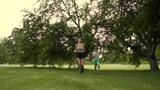 A jovem corre com a filha. mãe em conjunto com a criança entra para esportes na natureza — Vídeo de Stock