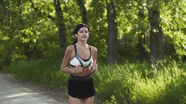 Chica sexy en una carrera. mujer joven corriendo por la carretera al atardecer. atleta trotando. cámara lenta — Vídeo de stock